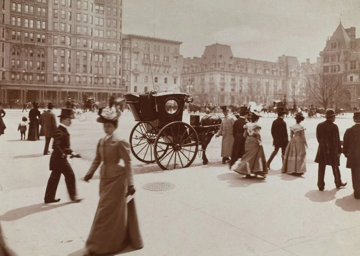 Early urban photography showing city life with pedestrians and horse carriage as visual reference