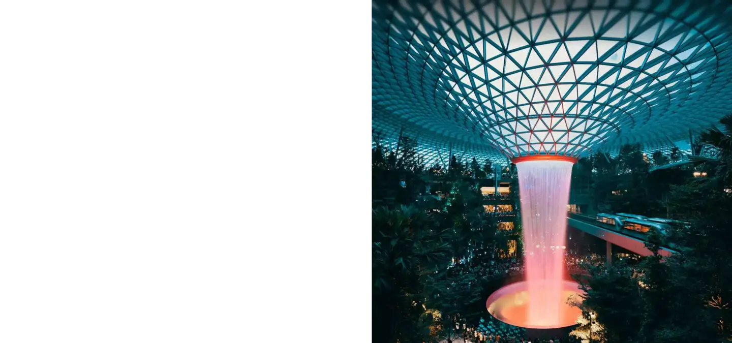 Indoor waterfall under glass dome with lush greenery, top 3D visualization studios in the Singapore market