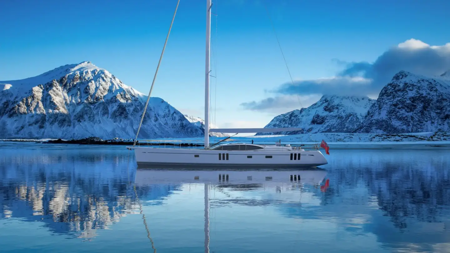 Sailing yacht anchored on still water with snow-covered mountains reflected on the surface