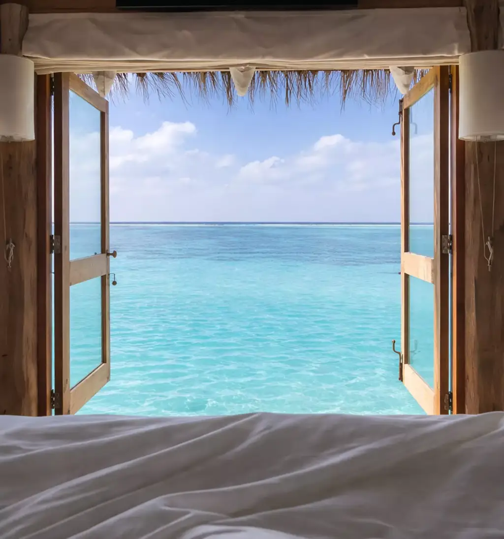 Visualización arquitectónica de una cama frente a puertas de madera abiertas a un mar turquesa en calma bajo un cielo suave y nublado