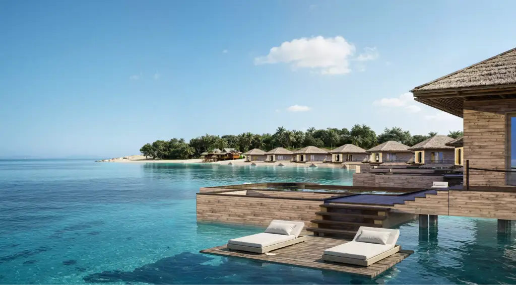 Visualización arquitectónica de villas sobre el agua y bungalós frente a la playa alrededor de una terraza privada con tumbonas sobre un mar turquesa.