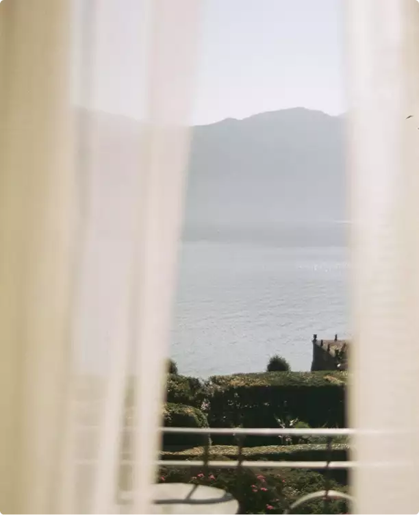Vista dell'animazione 3D della casa attraverso tende leggere verso l'acqua e le colline lontane