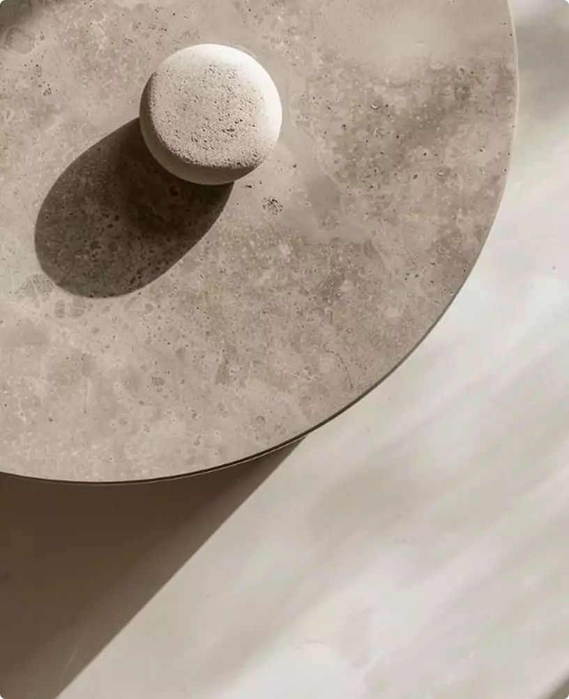 Visualizzazione di una caffetteria con superficie rotonda in pietra, pomello materico e ombra morbida su toni neutri