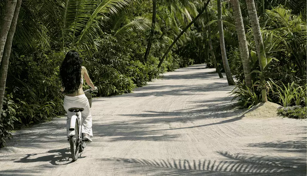 Fietser in een 3D-hotelrender op een zandpad door dichte palmen en tropisch groen
