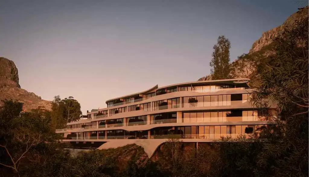 Hotel exterior of a terraced mountainside building with curved balconies, glass facade, and trees at sunset