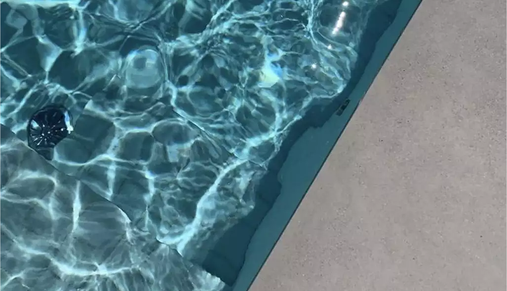 Superficie dell'acqua della piscina con riflessi del sole e bordo vasca in una casa contemporanea