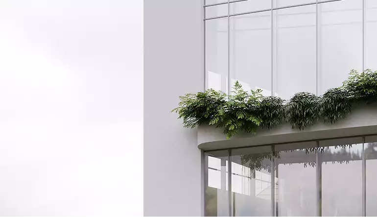 Hoek van de glazen gevel met de rand van een beplant terras