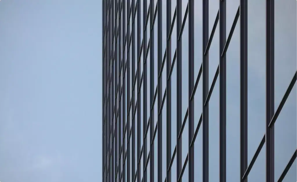 Borde de fachada en un render de rascacielos con montantes verticales oscuros y vidrio reflectante contra un cielo azul pálido.