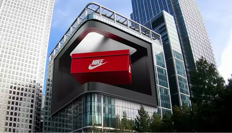 Animazioni fooh in CGI 3D su un maxischermo curvo, con una scatola Nike rossa sospesa sopra l'edificio