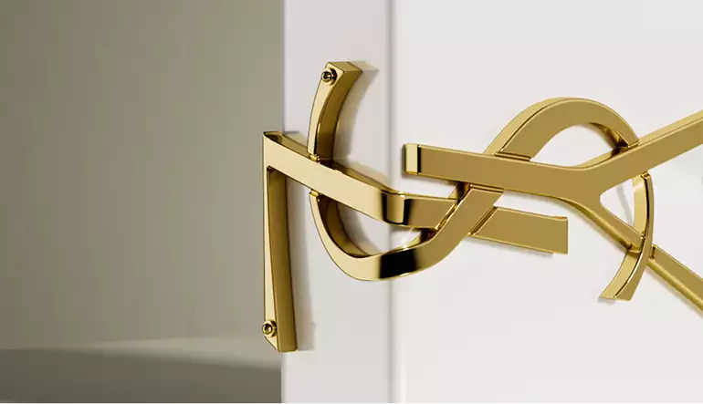 Detalle de logotipo dorado en primer plano sobre frasco de perfume blanco con acabado metálico e iluminación suave, render 3D