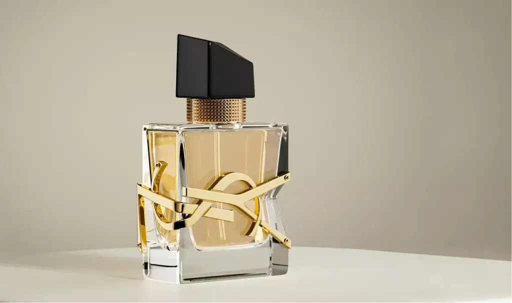 Frasco de perfume centrado sobre un pedestal redondo con detalle dorado y fondo neutro, render 3D de cosmética