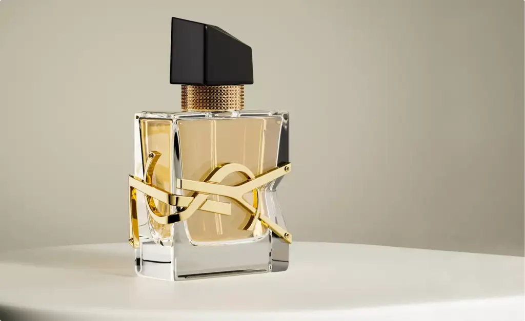 Frasco de perfume de vidrio transparente con detalle dorado sobre pedestal redondo y fondo neutro, render 3D de cosmética