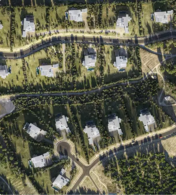 Luftbildvisualisierung: Draufsicht auf eine Villensiedlung mit Zufahrtsstraßen und Baumbestand