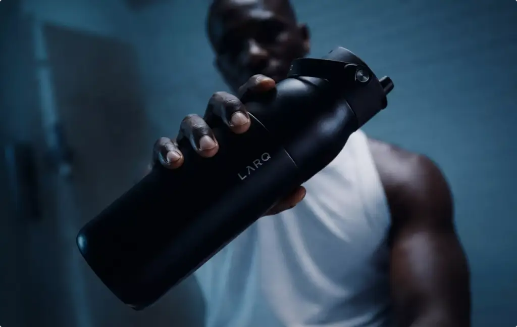 3D Product Rendering of black reusable bottle held by person in low light setting