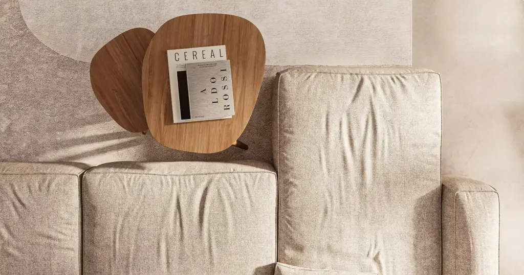 Beige bank in het appartementinterieur met kleine houten tafels en boeken erop