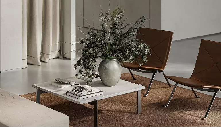 3D-visualisatie van kledingwinkel met salontafel, boeken, plantenvaas en moderne zit op een getextureerd vloerkleed