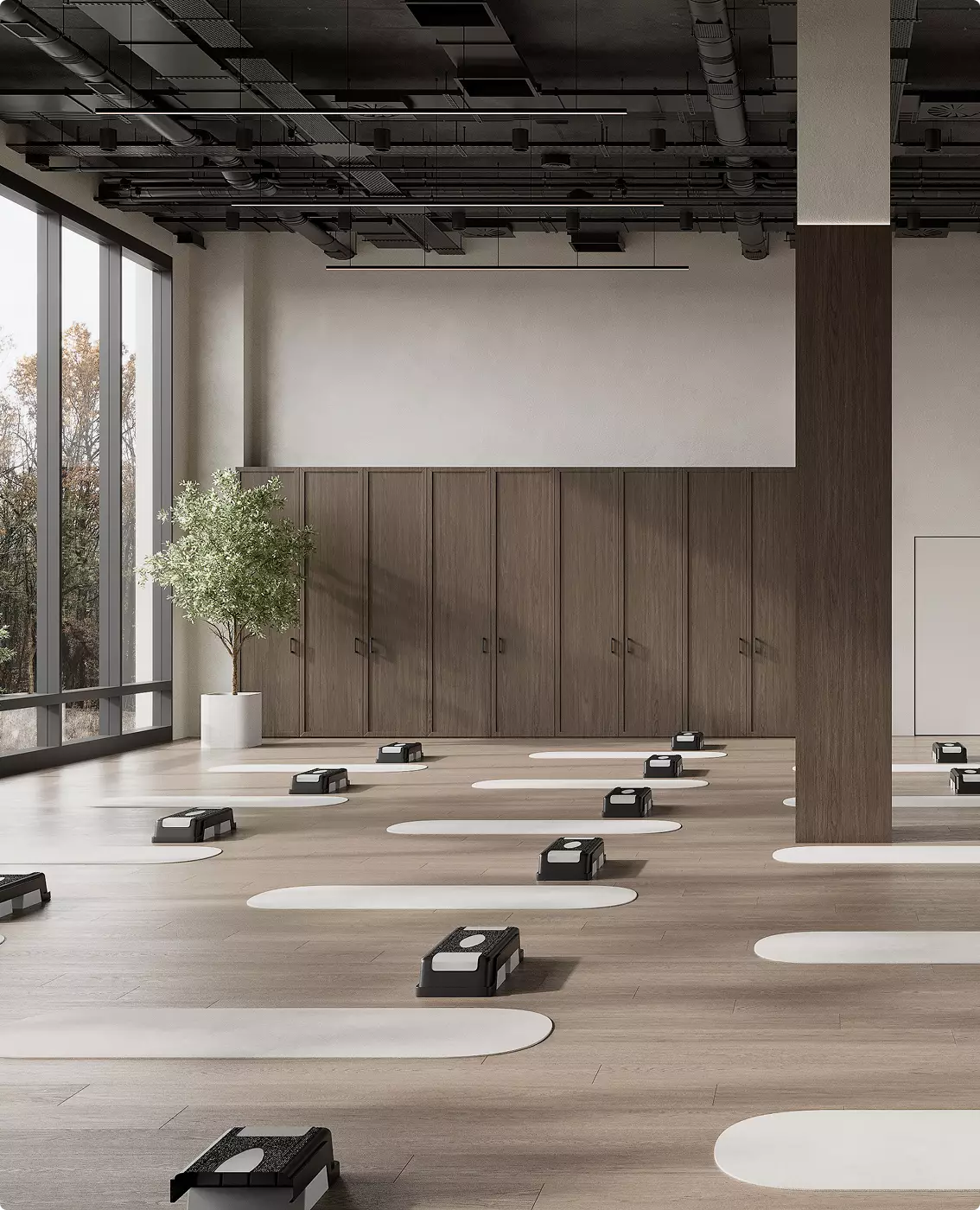 Sala corsi di gruppo nel design di una palestra commerciale con step, pavimento in legno e grandi vetrate