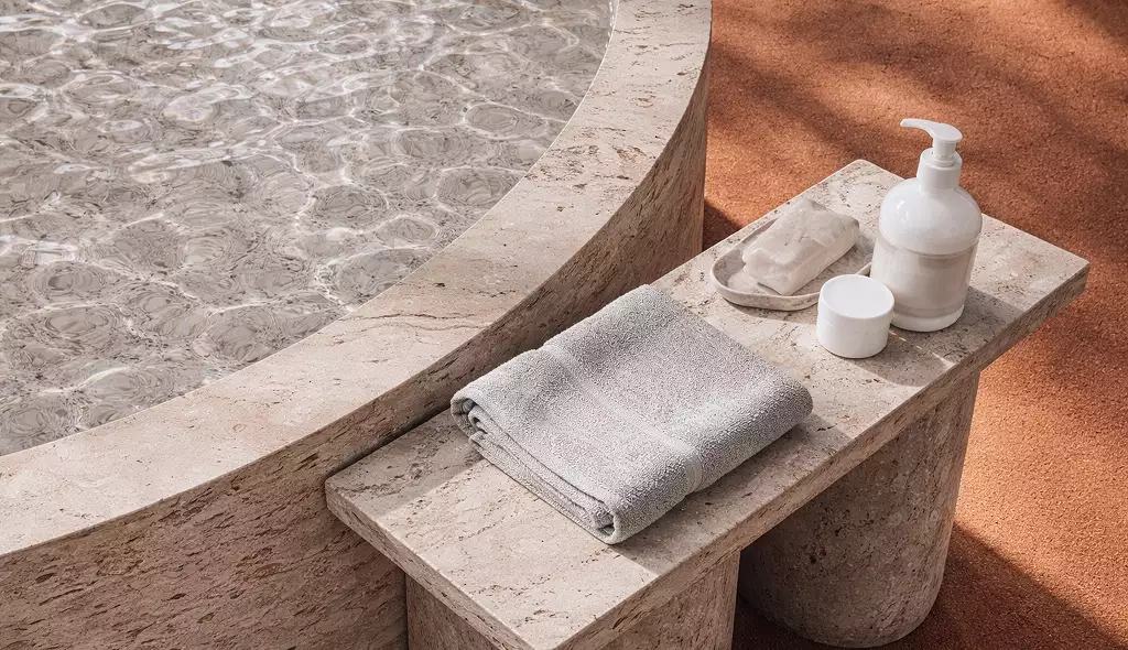 Detalle de spa en la visualización del resort: pila de piedra con agua, toallas y amenidades