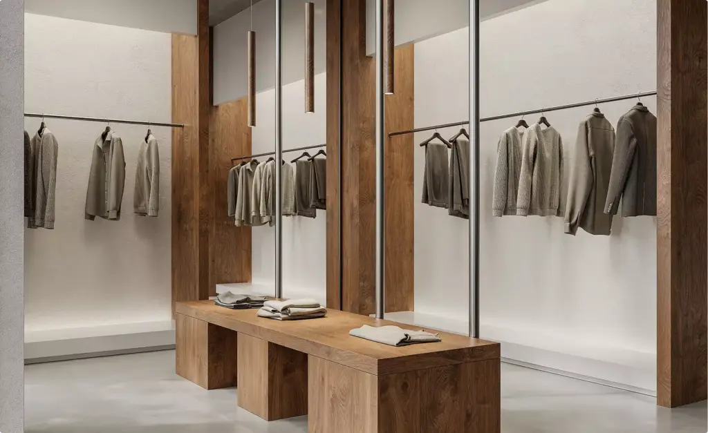 Interieurontwerp van modewinkel met houten displaytafel, hanglampen en netjes geschikte kledingstukken