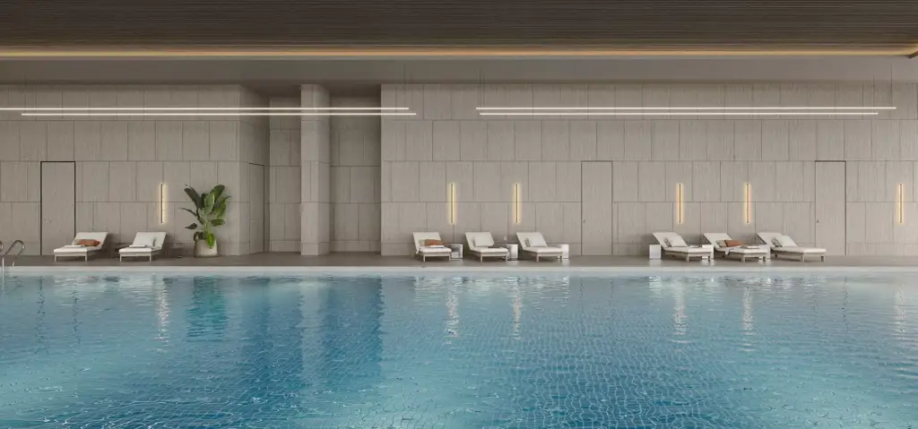 Area piscina interna nell'interior design di un centro fitness con lettini, pareti piastrellate e superficie dell'acqua calma