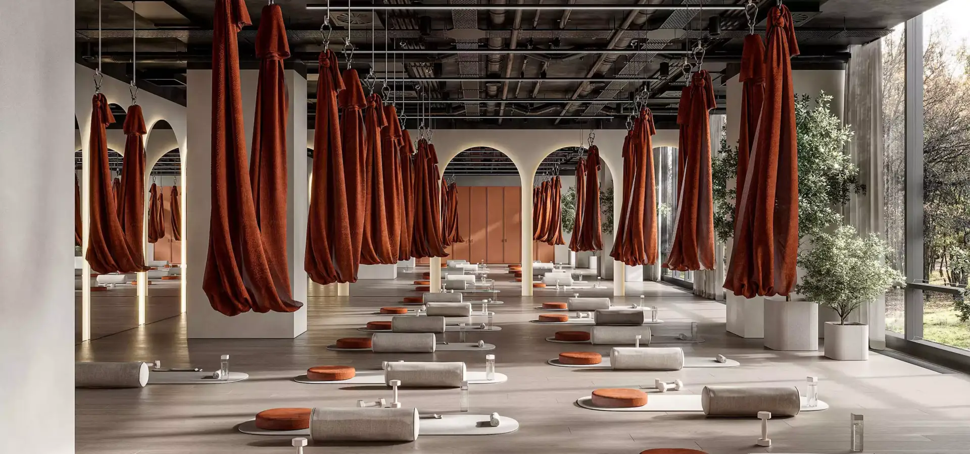 Sala yoga simmetrica nell'interior design di un centro fitness con amache, archi, tappetini e toni neutri