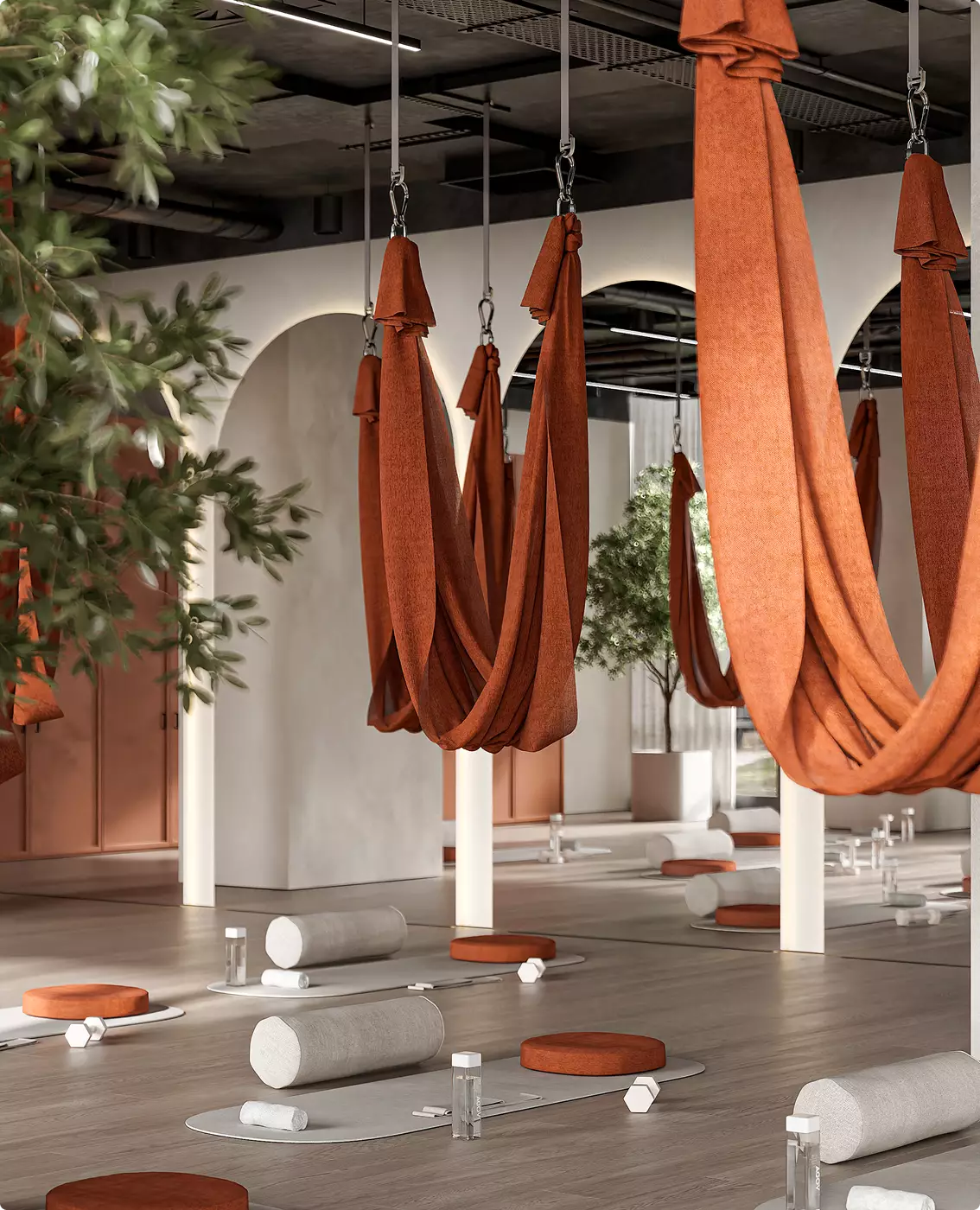 Spazio di yoga aereo nell'interior design di un club fitness con amache appese, tappetini e luce naturale morbida