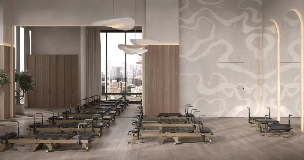 Studio pilates nell'interior design di un club fitness con reformer, specchi, pannelli in legno e grande finestra