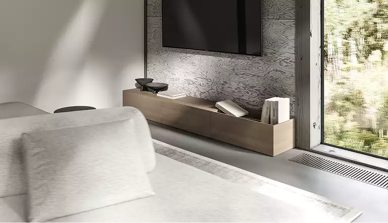 Woonkamer van het boshuis met bank, wandtelevisie en houten dressoir bij een groot raam