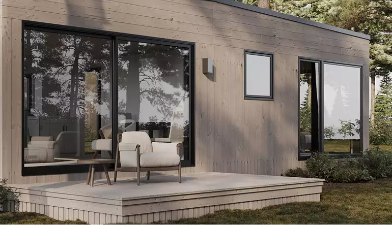 Modern boshuis-exterieur met houten gevel, terrasstoelen en grote glazen deuren in een dennenbos