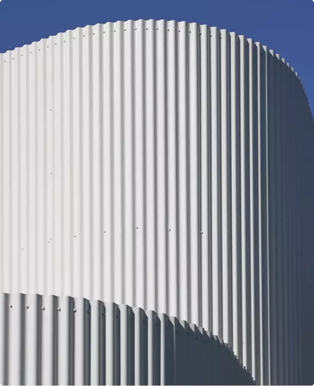 Rendering 3D industriale, primo piano di una facciata metallica curva con costoloni verticali contro il cielo azzurro