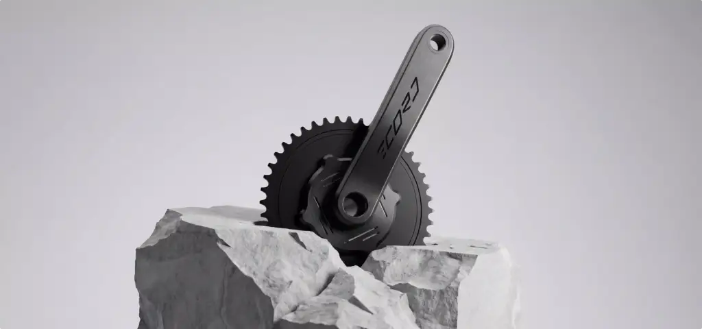 Render de una biela de bicicleta negra apoyada sobre una piedra clara