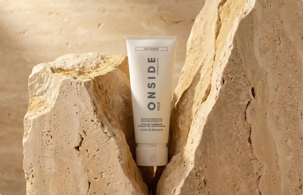 Render of a white skincare tube standing in a split block of travertine under warm light