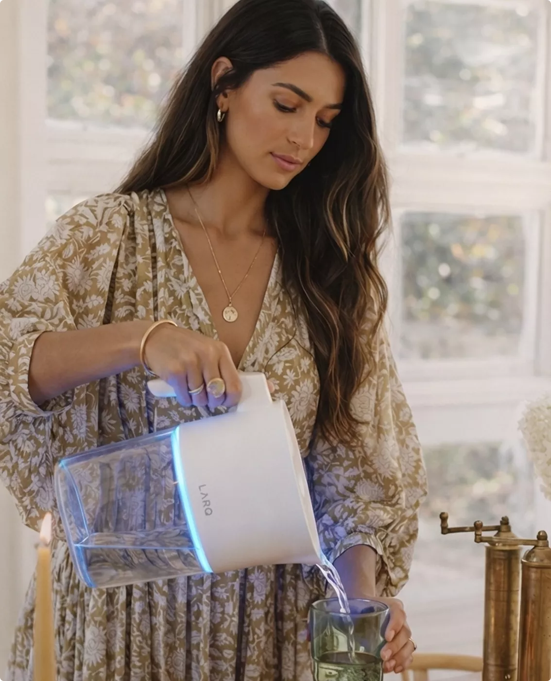 Visualizzazione della caraffa LARQ bianca illuminata mentre una donna versa l'acqua in un bicchiere