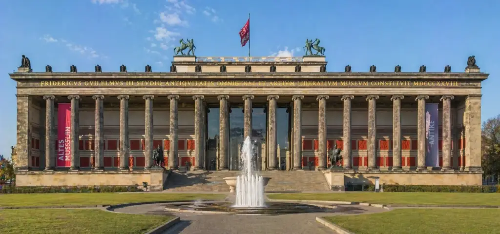 Fachada de museo neoclásico con columnas altas y una fuente en el eje central