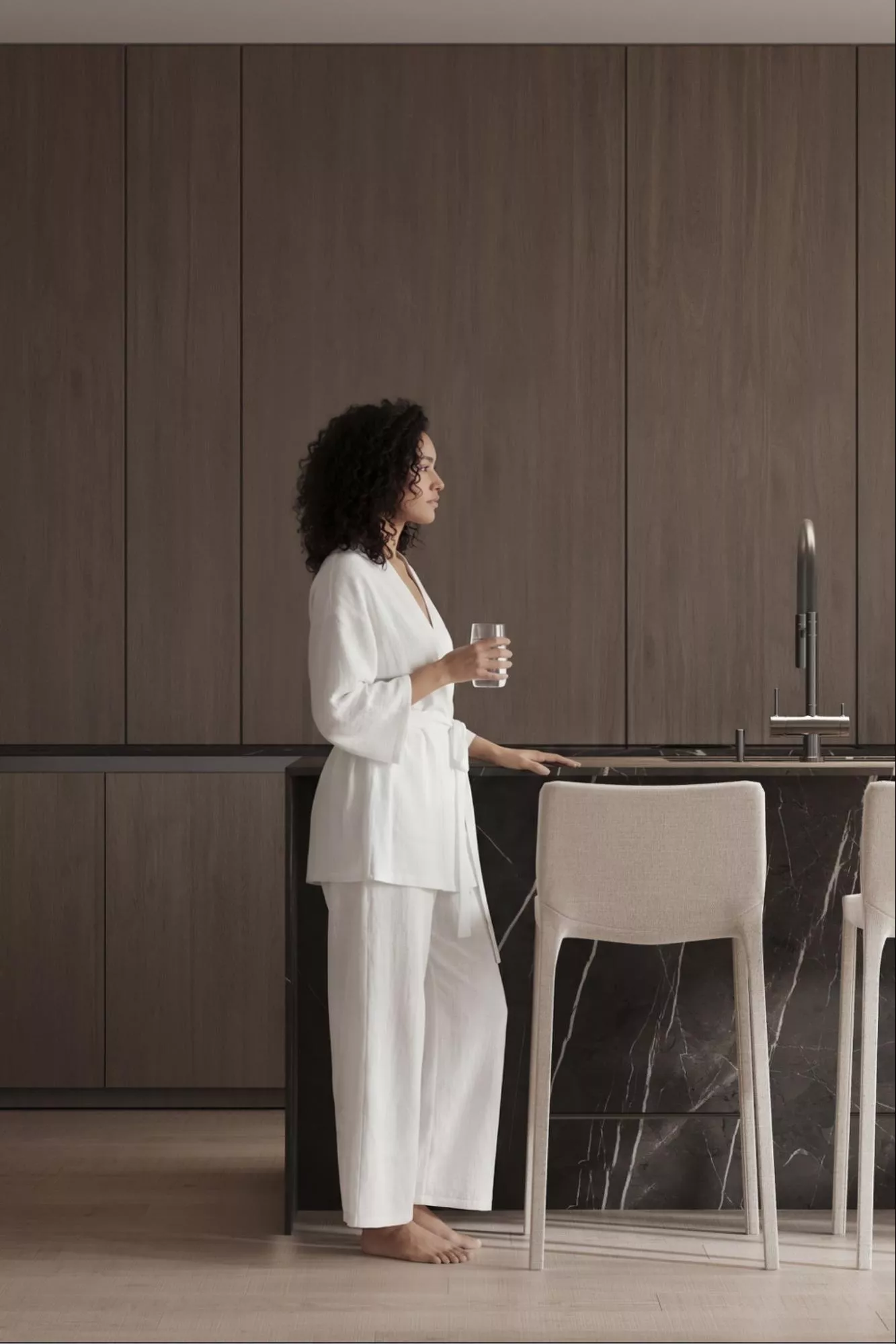 Photorealistic kitchen render with dark wood cabinets and woman beside black marble island