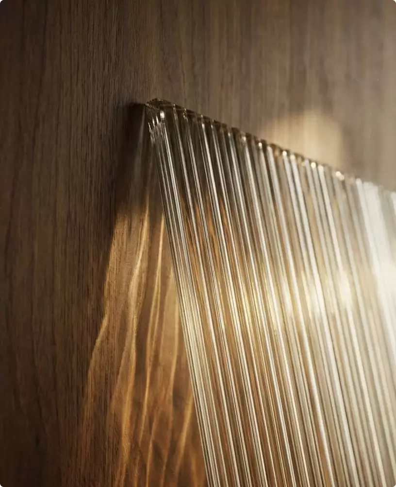 Light passing through ribbed glass casting patterns on wood, wall light visualization.
