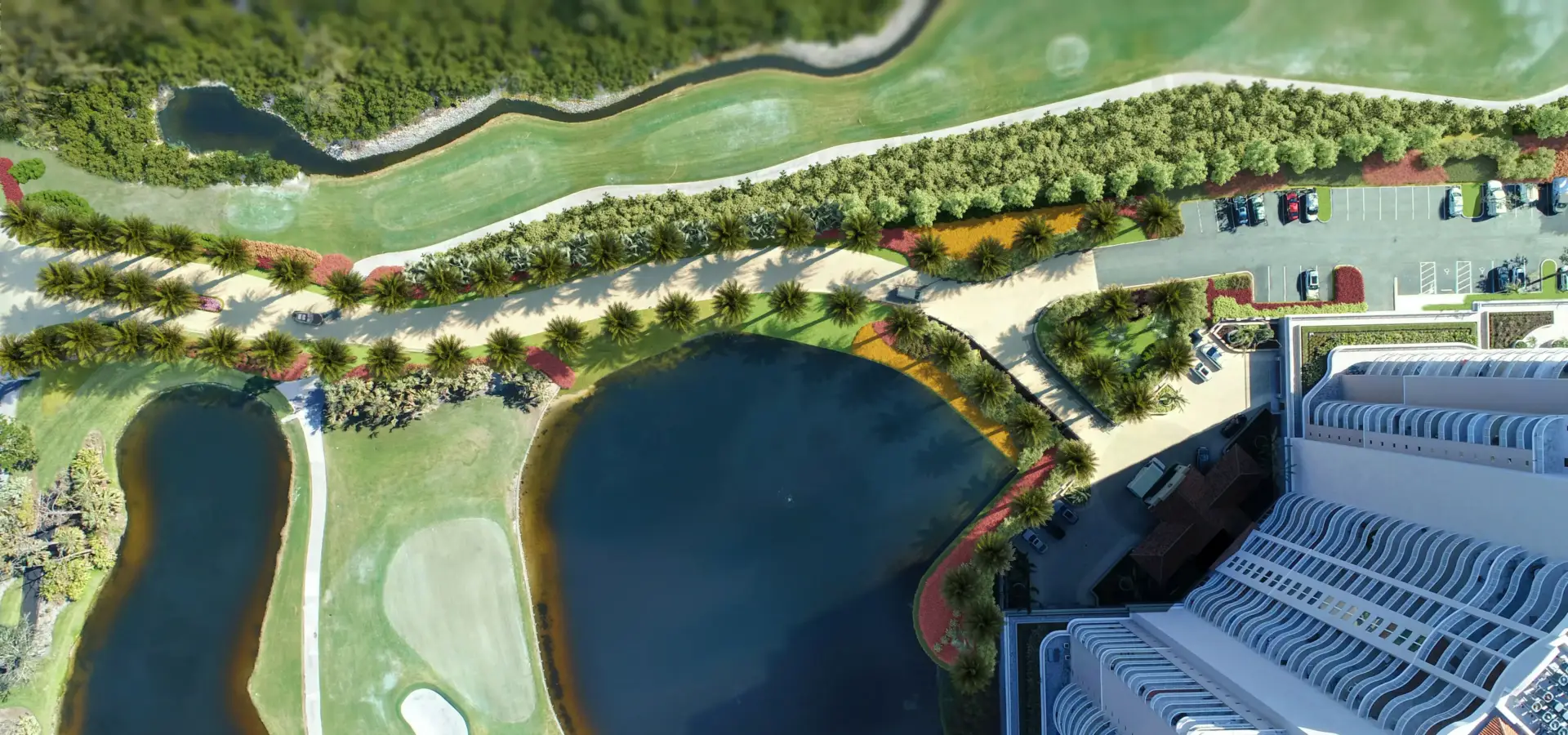 Top-down aerial rendering of a resort site with lakes, landscaped paths, palm trees and parking