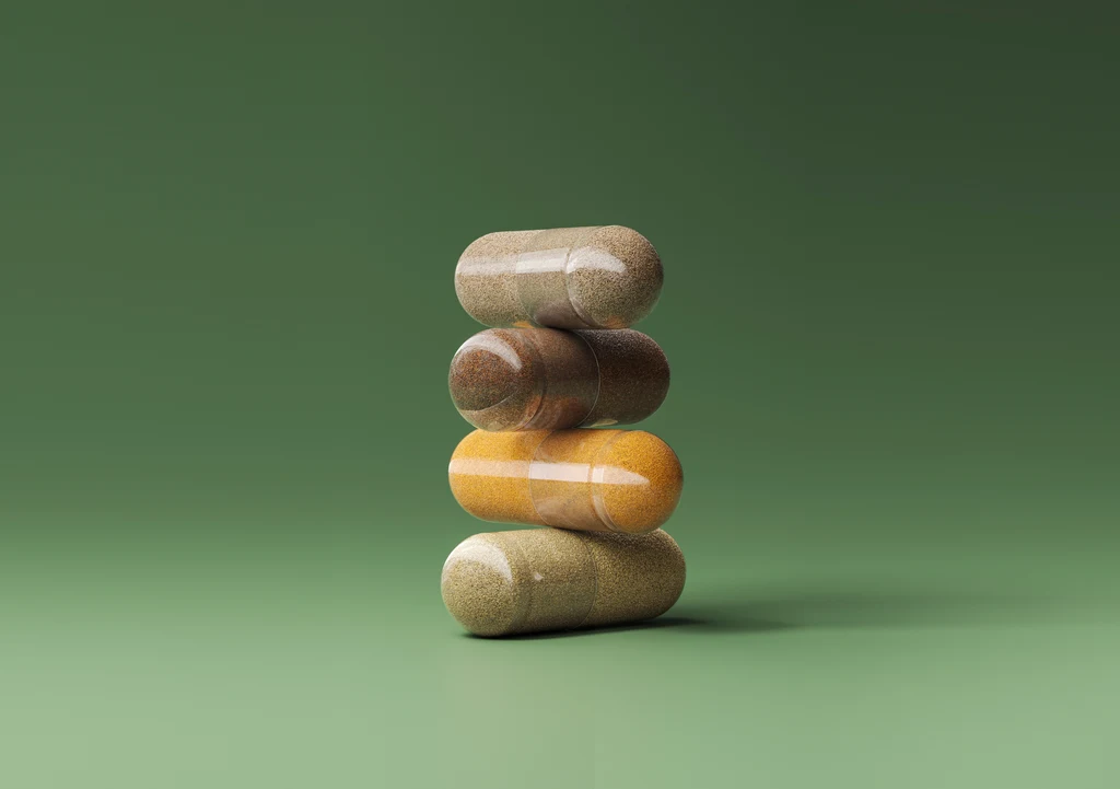 Vier doorzichtige capsules op elkaar gestapeld, gevuld met verschillende ingrediënten in poedervorm, op een groene achtergrond
