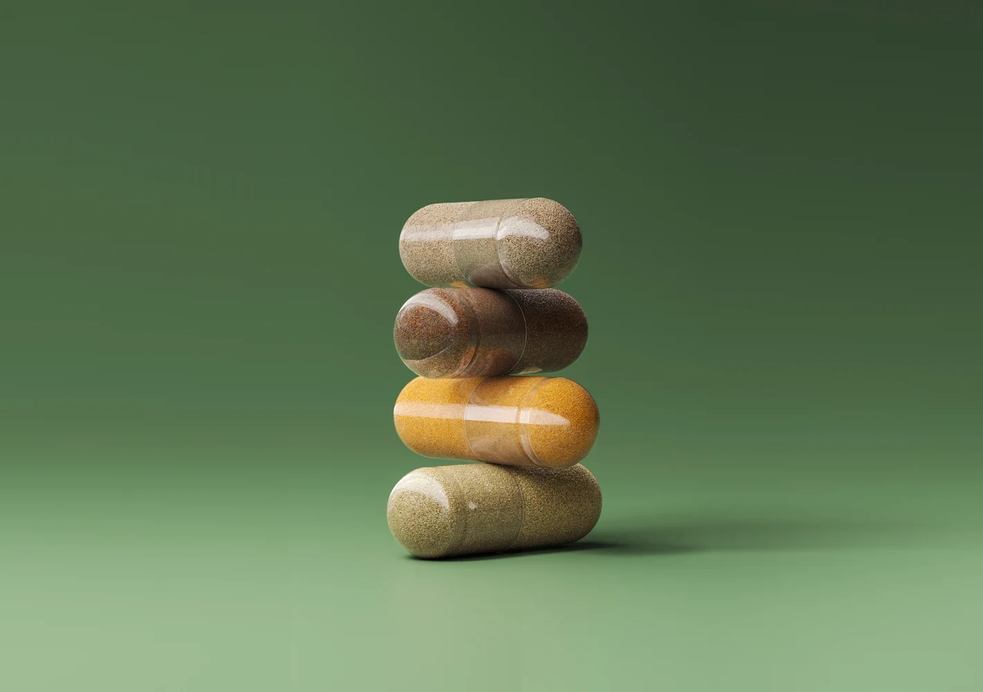 Stack of four clear capsules filled with different powdered ingredients on a green background