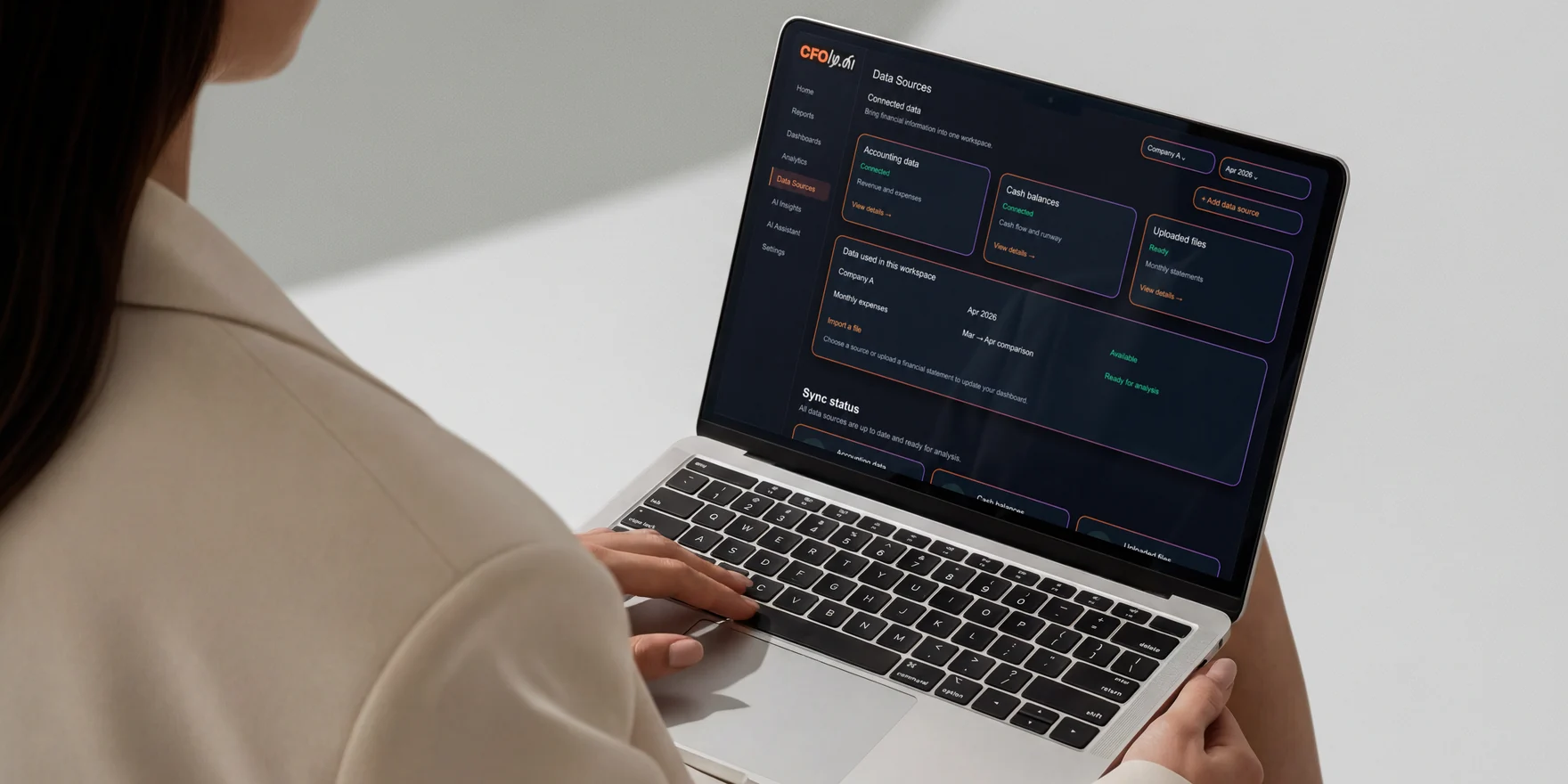 Donna in blazer chiaro al lavoro su un laptop con la schermata delle fonti dati di un’app AI CFO