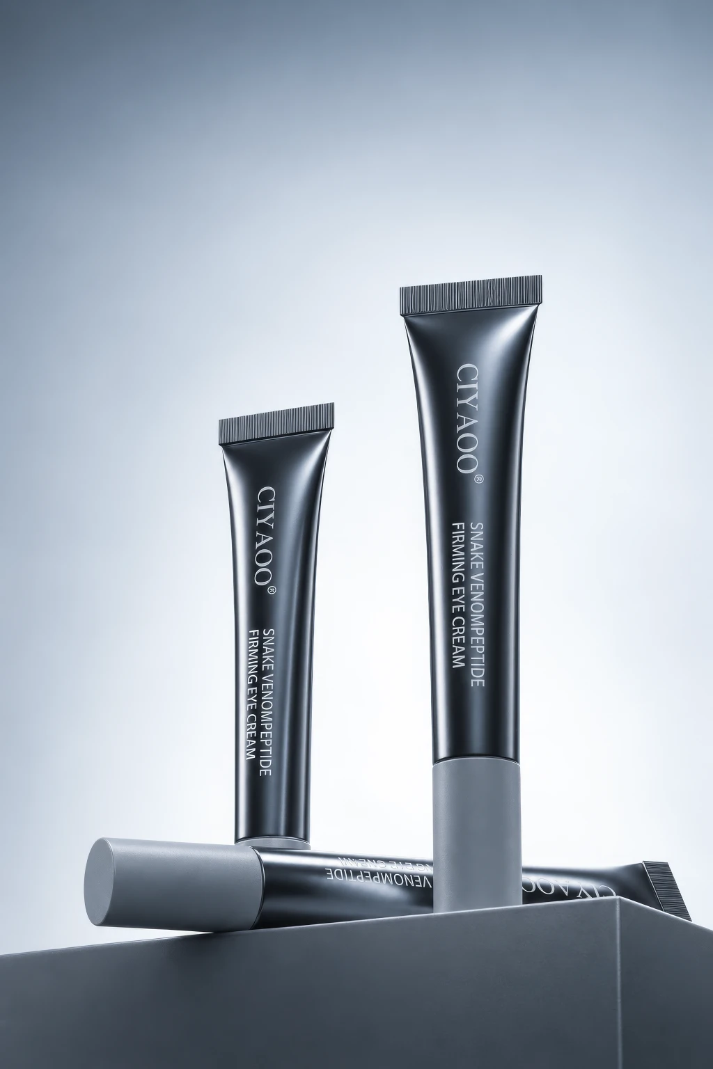 3D rendering of black tubes of eye cream on a grey surface against a gradient background.
