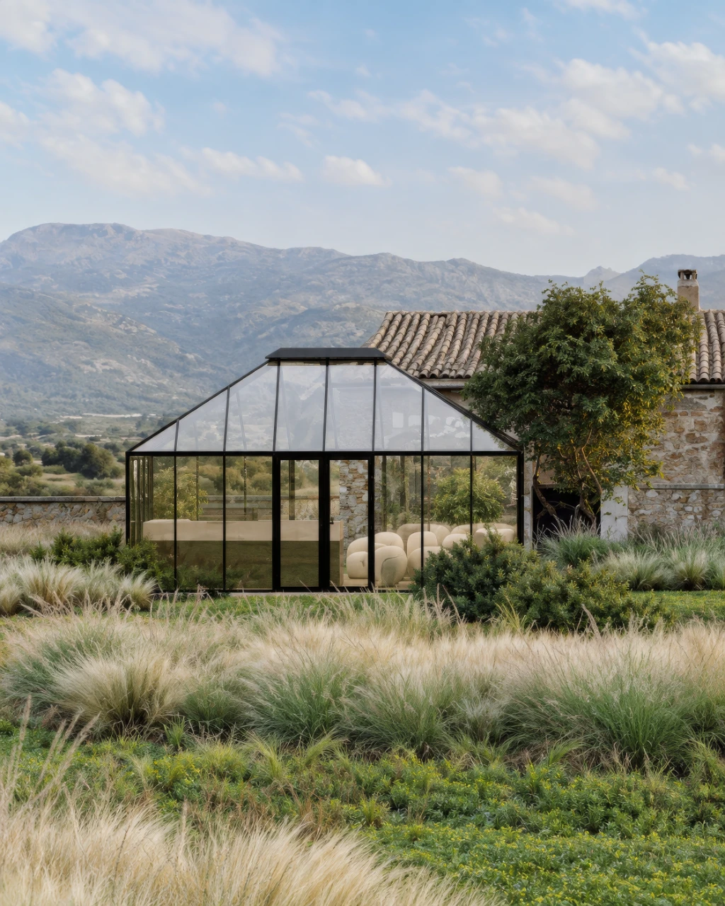 3D rendering of a modern glass conservatory extension on a stone house with mountainous landscape background.