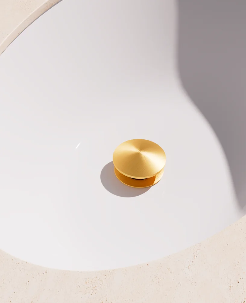 Render of a basin pop-up waste in aged gold inside a white ceramic basin, seen from above
