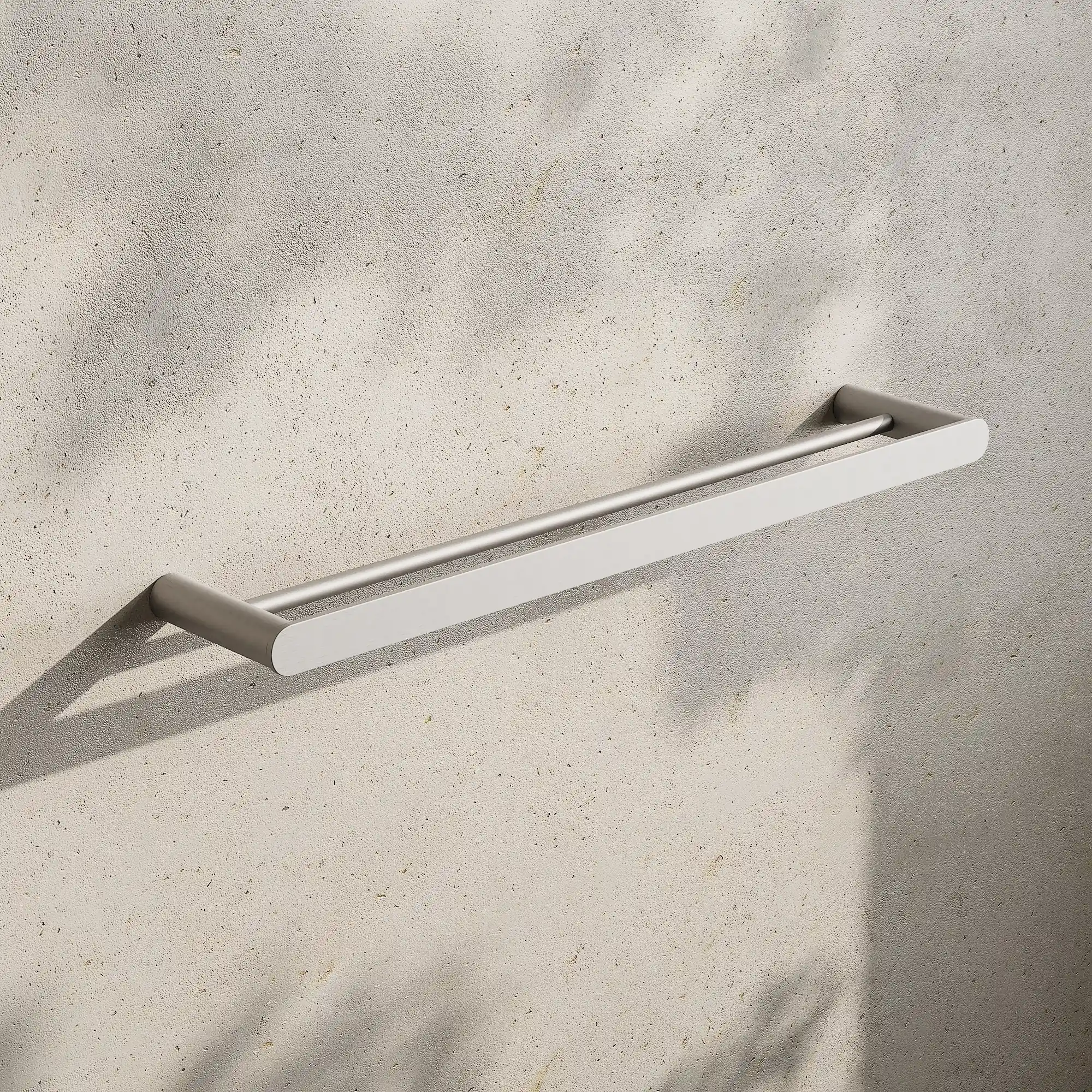 Render of a double towel rail in brushed stainless on a stone wall with leaf shadows