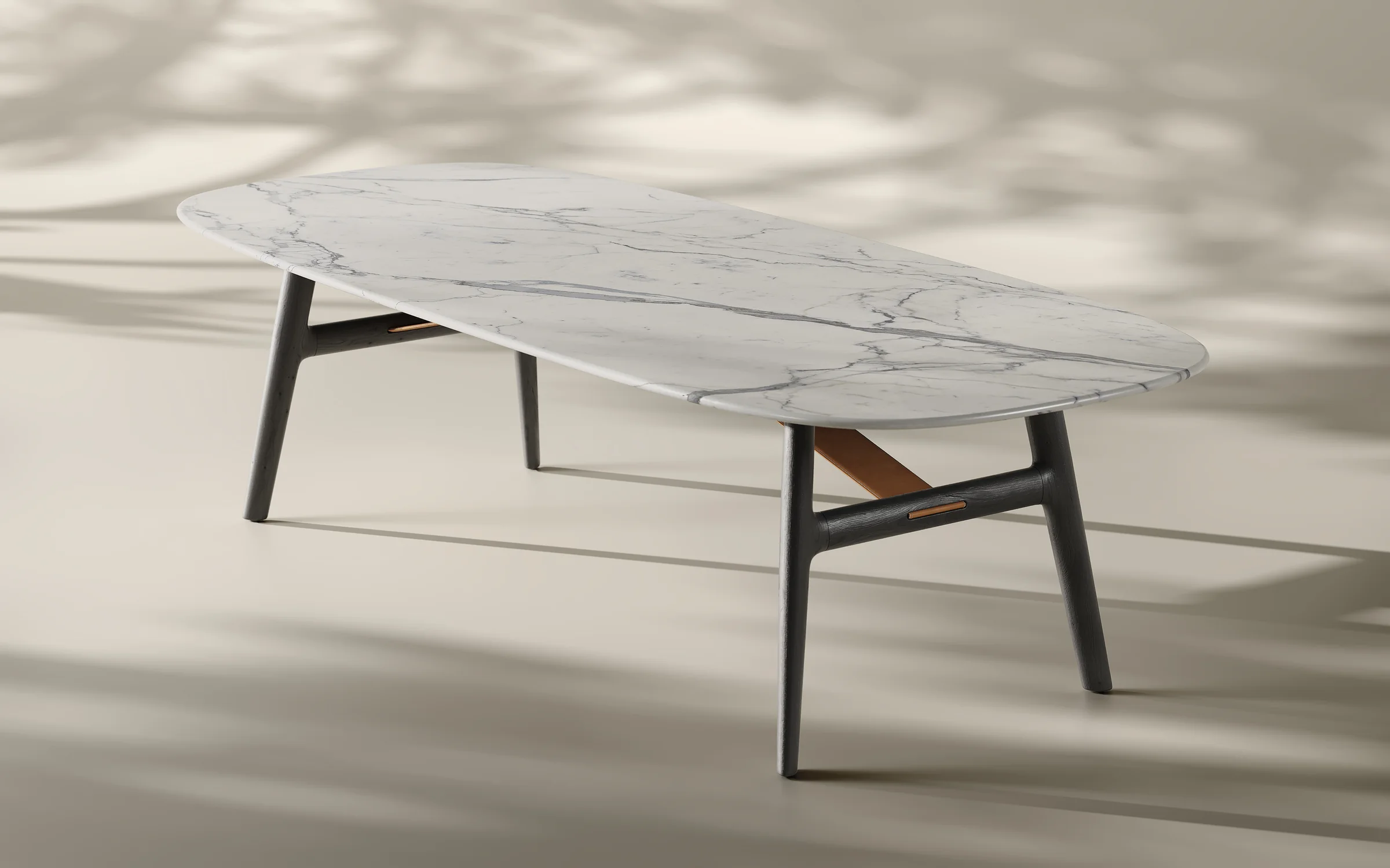 Render of an oval dining table with a white marble top on a dark-stained wooden base in soft daylight with leaf shadows