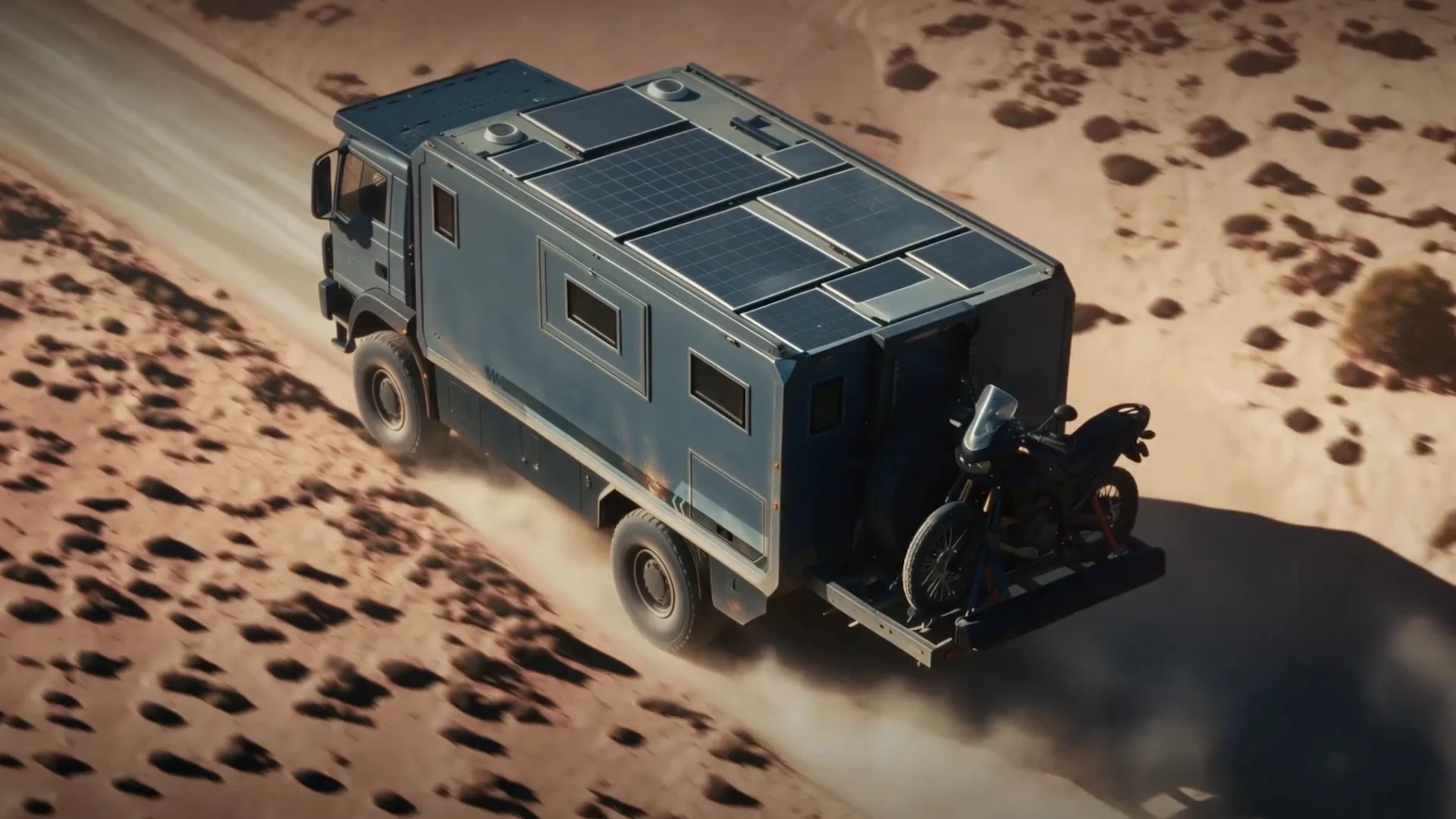 Top-down view of an expedition truck with a motorcycle on the rear rack on a desert track