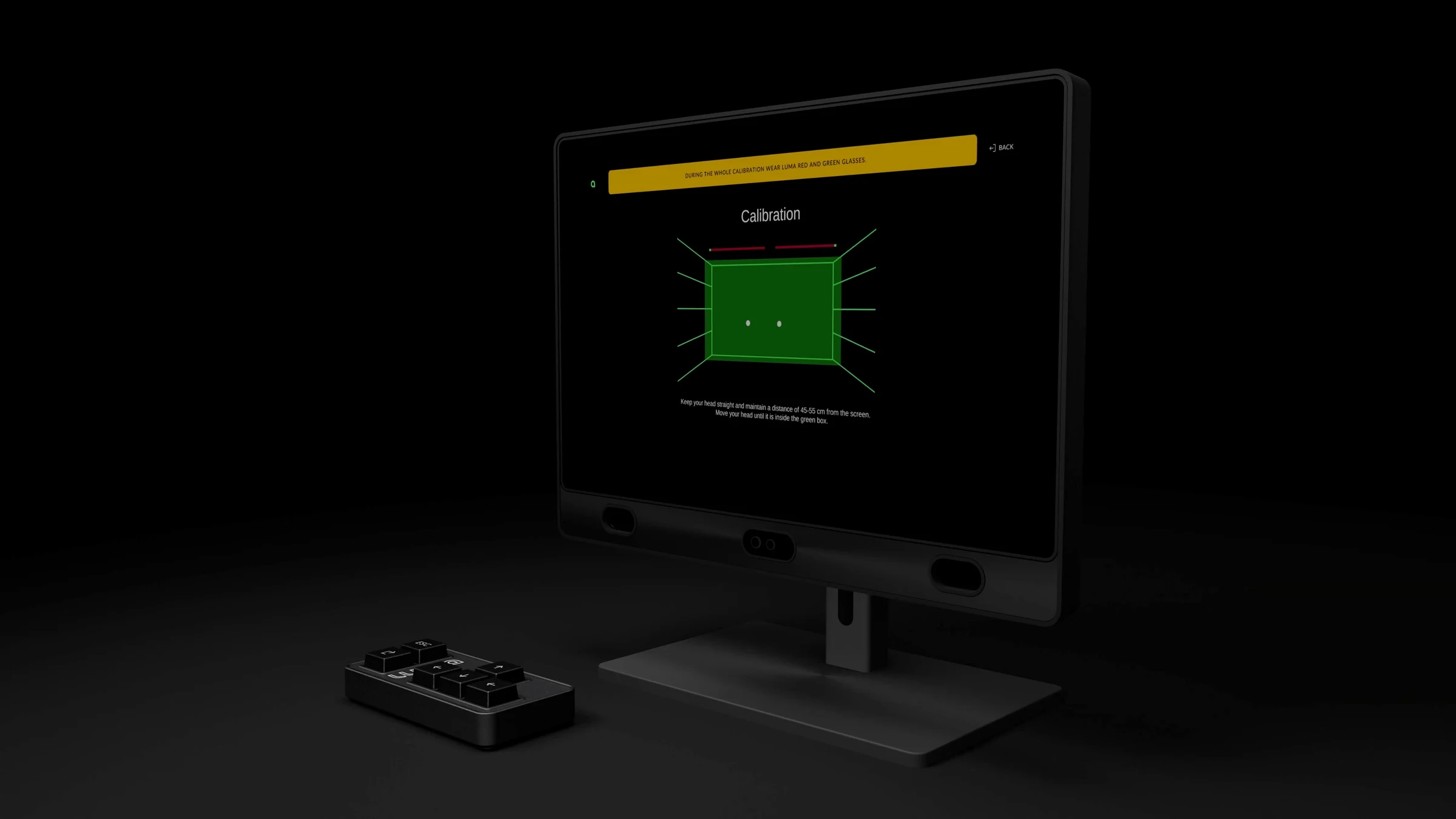 Eye tracker screen showing a green calibration grid, with the keypad in front on a dark set