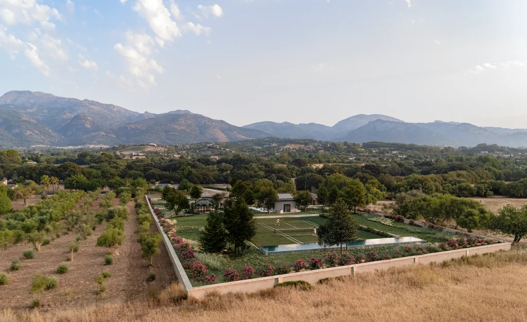 Aerial render of a renovated Mallorca finca with its garden, pool and grass tennis court set into a drone photo of the hills