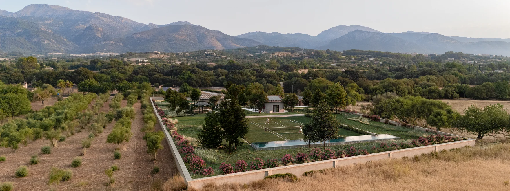Drone aerial render of a renovated Mallorca finca with a walled garden, grass tennis court and raised pool below the Tramuntana mountains