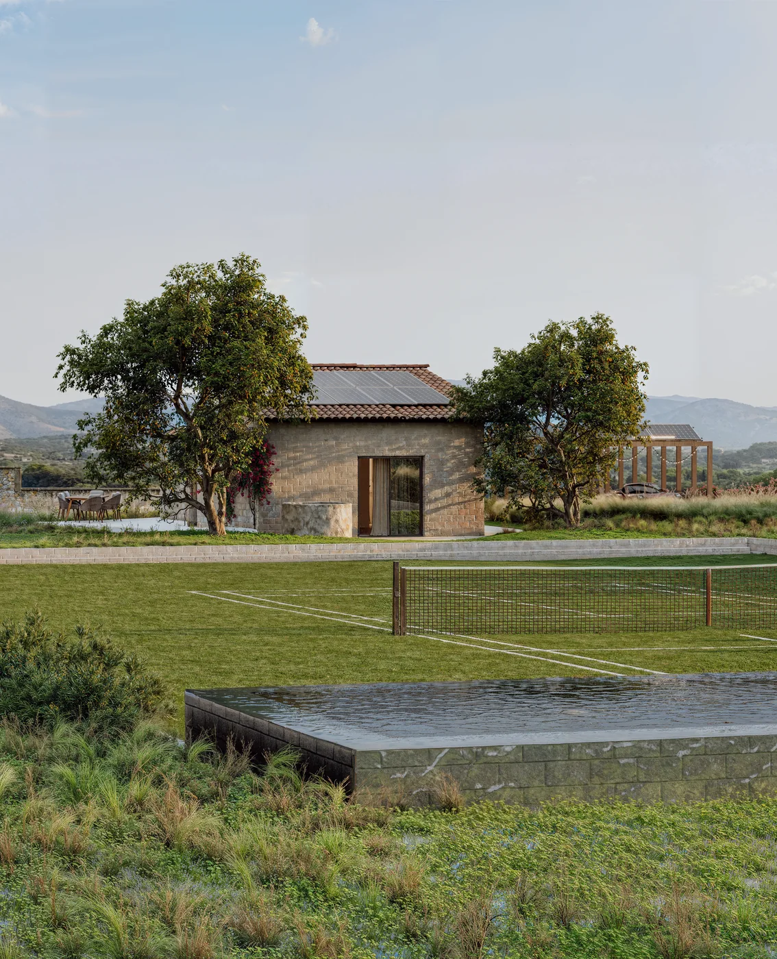 Portrait render of a renovated stone house behind a grass tennis court and stone-clad pool on a Mallorca finca